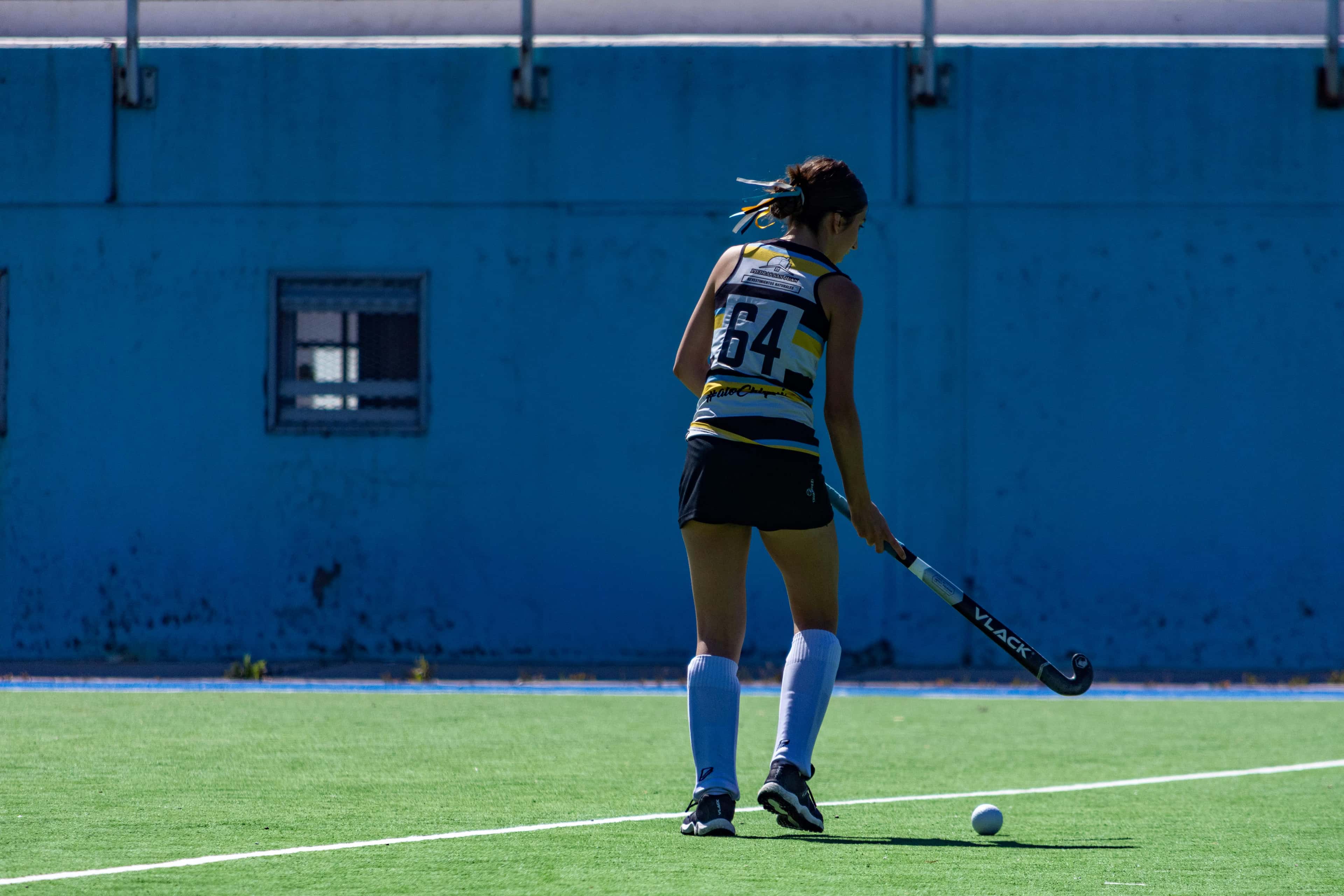Custom field hockey socks category cover image showing player sprinting on blue turf