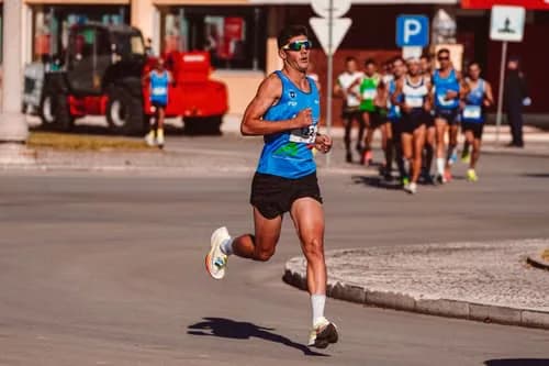 Road race runner in a blue singlet leading a group