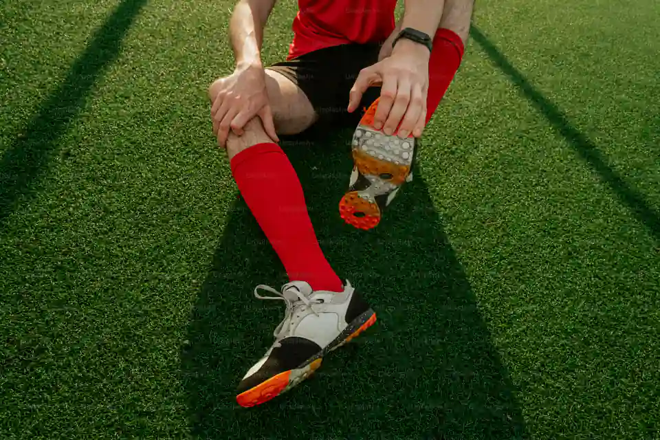 Soccer player wearing long red performance socks and cleats on the pitch