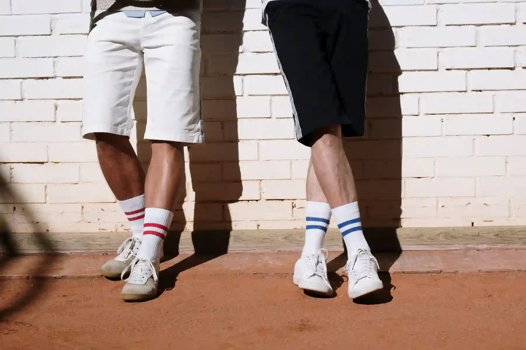 Two people wearing white striped tennis socks and white shoes