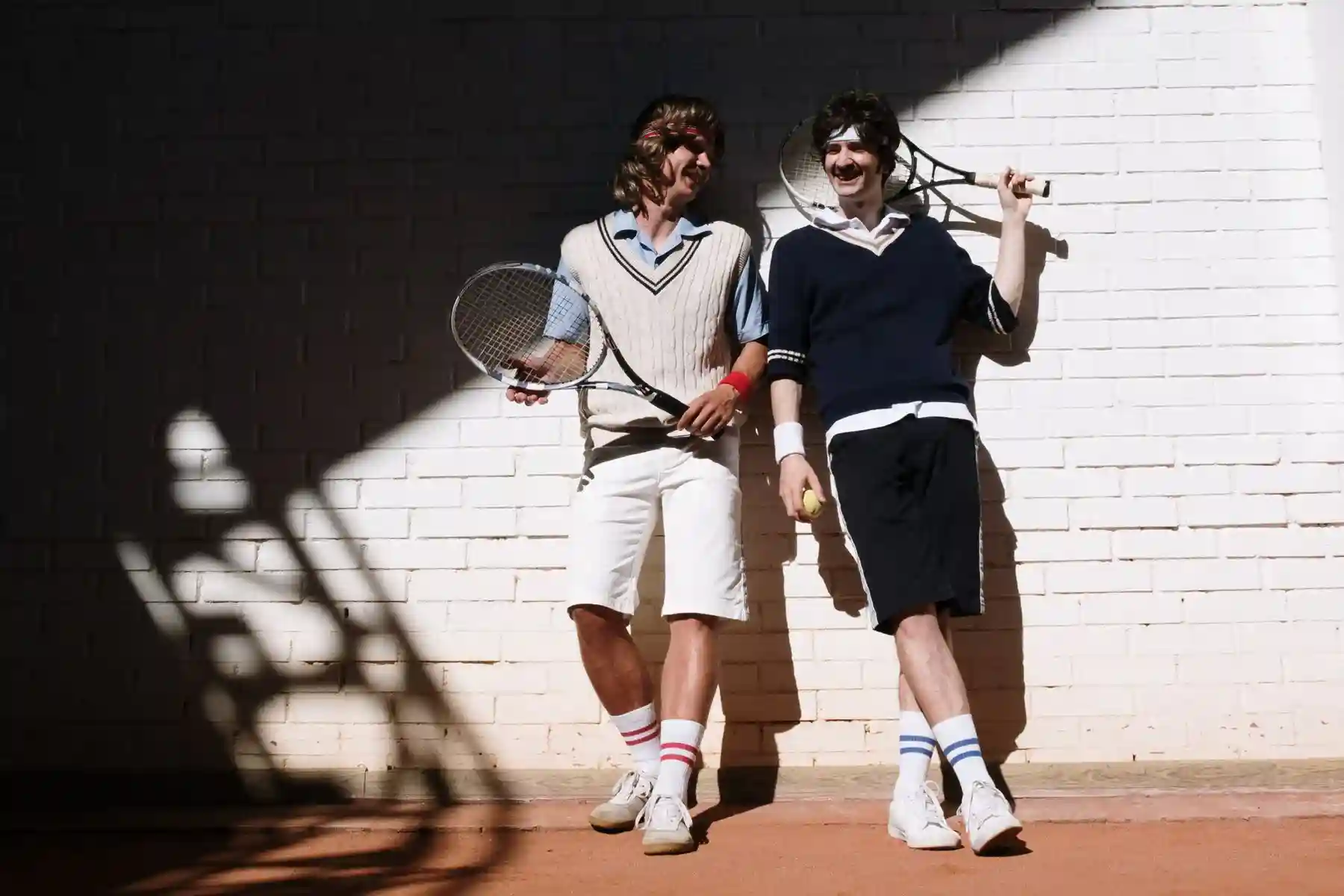 Two tennis players wearing white striped socks beside a court
