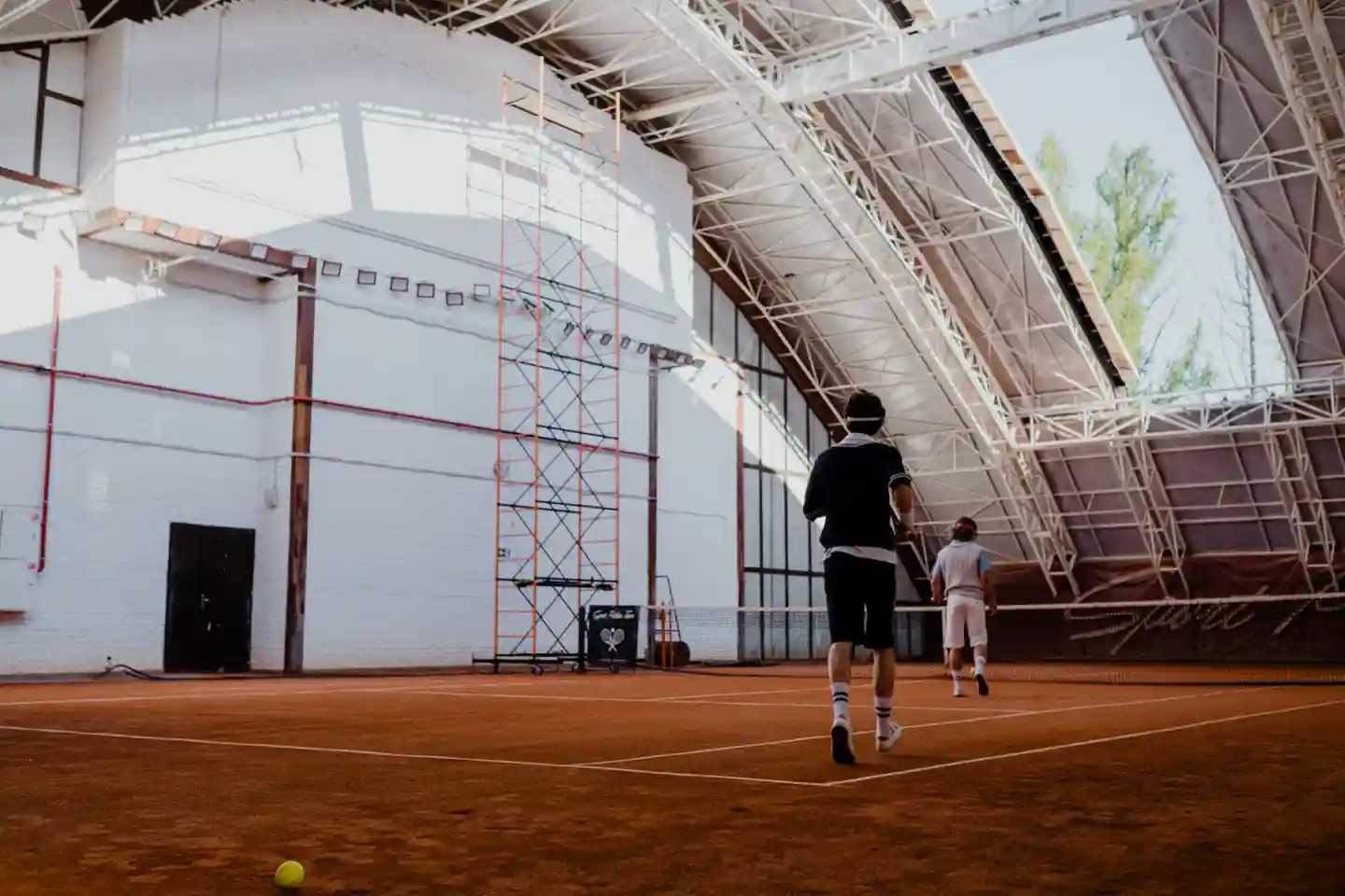 Two tennis players in white socks walking across an indoor clay court