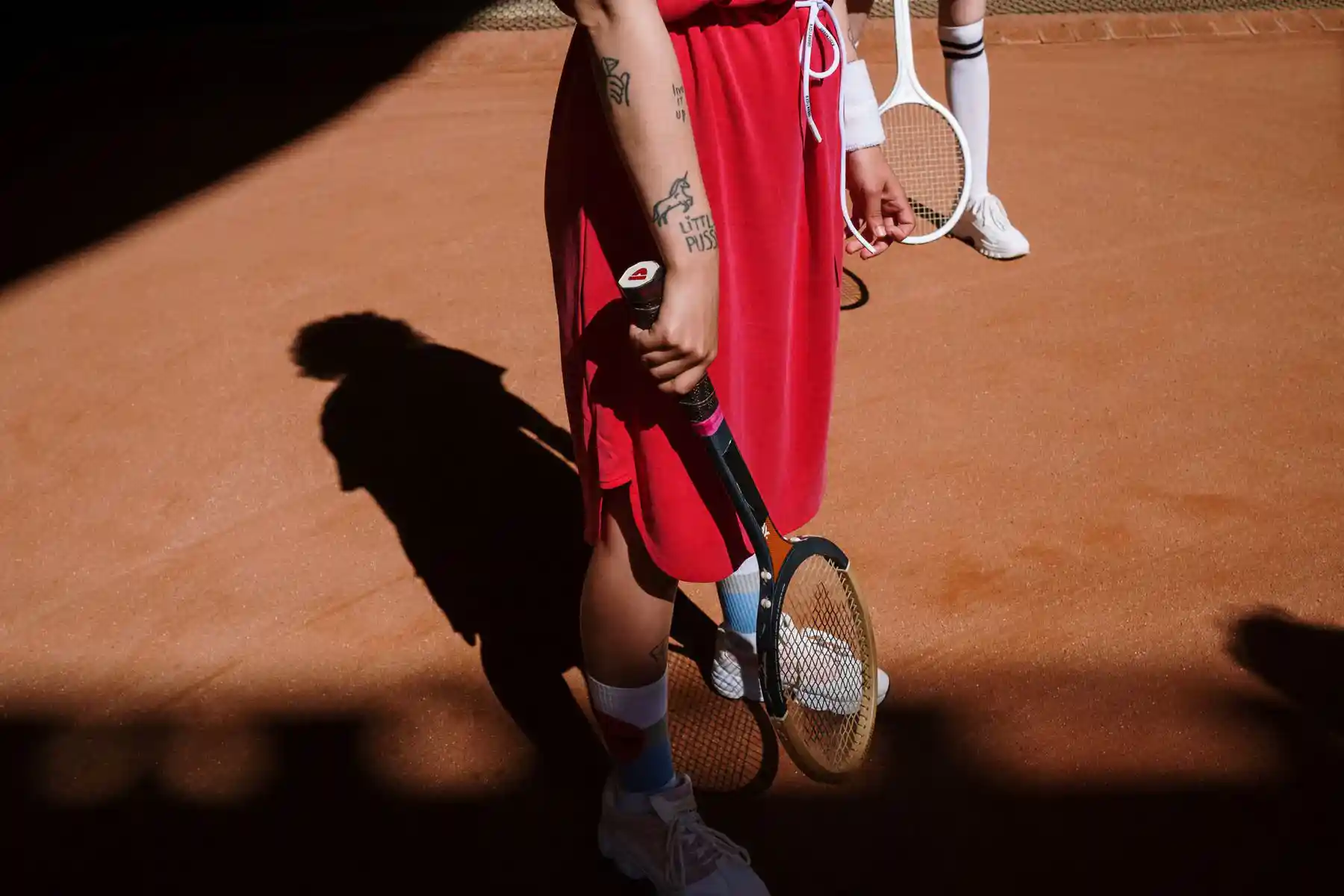 Tennis player in motion wearing white socks on a red court